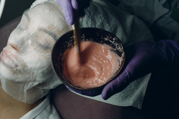 The process of preparation of pink alginate mask for face Cup in the hands of a beautician