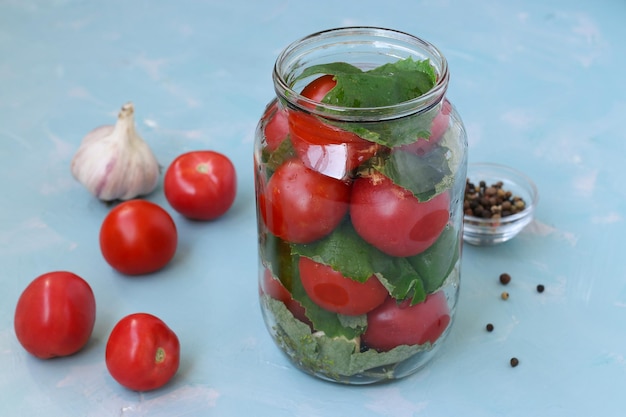 The process of preparing pickled tomatoes with grape leaves and garlic Location on blue background