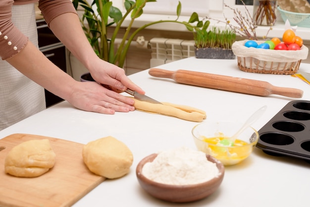 The process of rolling out the dough at home on the table is the hands of a woman for making cruffins festive pastries for Easter