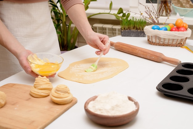 The process of rolling out the dough at home on the table is the hands of a woman for making cruffins festive pastries for Easter