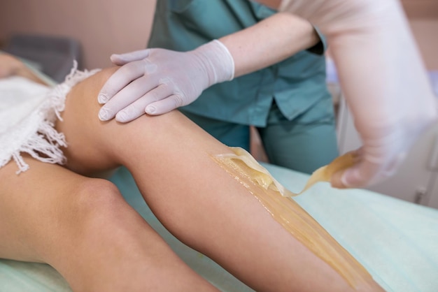 The process of shugaring legs in a beauty salon The concept of grooming the case removing unwanted hair