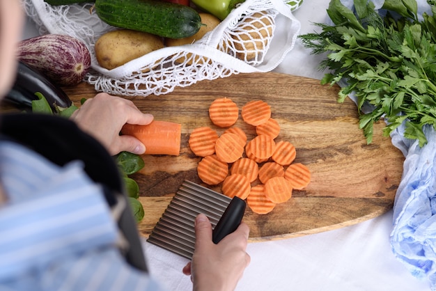 Process of slicing carrots with wavy fluted knife quilling vegetables in string bag