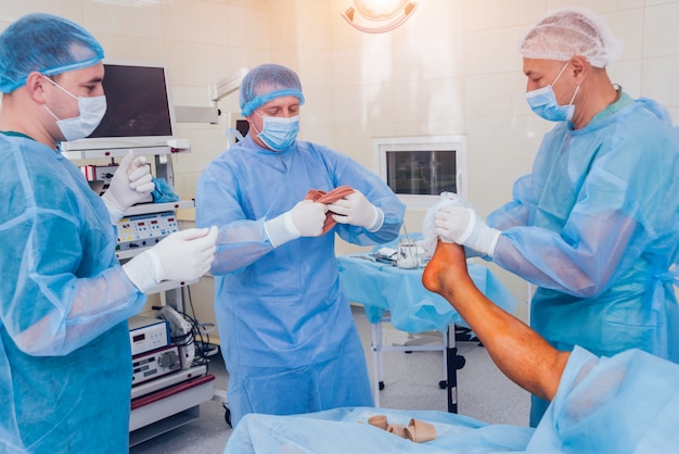 Process of trauma surgery operation. Group of surgeons in operating room with surgery equipment.