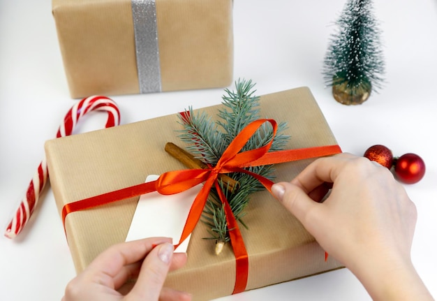 The process of tying a red ribbon on a Christmas gift box Gift design concept