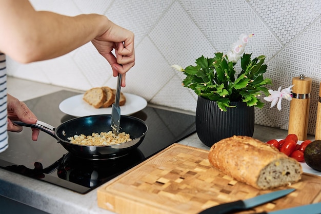 Process of woman cooking breakfast at kitchen female hands preparing omelet in frying pan using indu