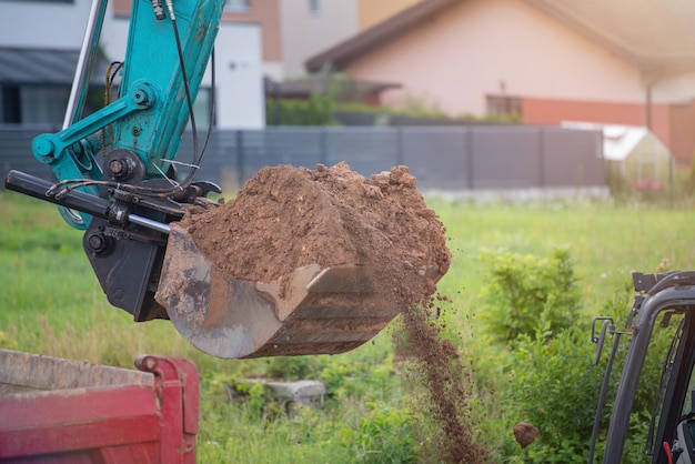 The process of working heavy construction equipment A big blue excavator is pouring earth into a truck Road works reconstruction of the road surface High quality photo