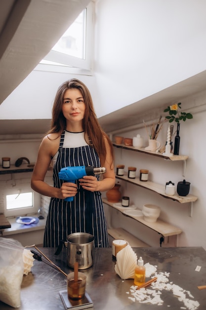 Photo production of candles a woman dries wax with a hair dryer