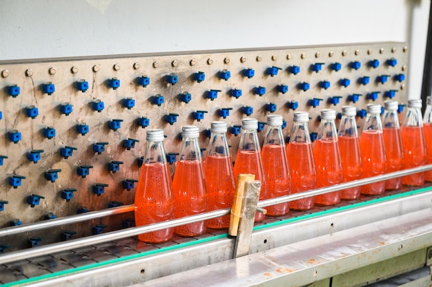 Production line of bottled juice beverage moving on conveyor belt in beverage processing factory