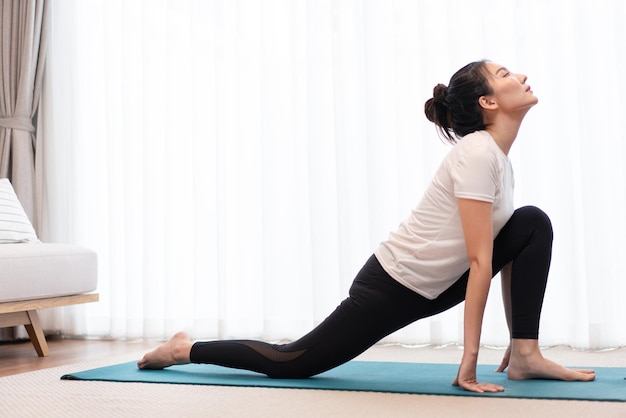 Productive activity concept a female young adult practicing the flexibility of her body by doing mat pilates exercise.