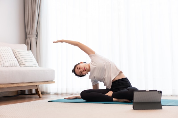 Productive activity concept a female young adult wearing a white t-shirt practicing the flexibility of her body by doing mat pilates.