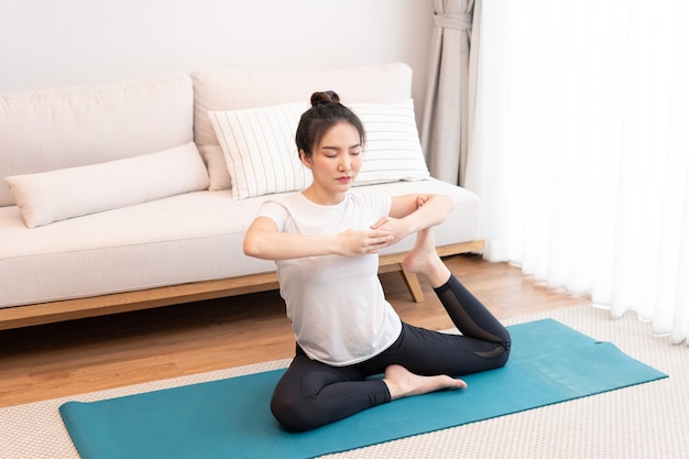 Productive activity concept a girl with a bun wearing the white t-shirt doing the difficult pilates move.