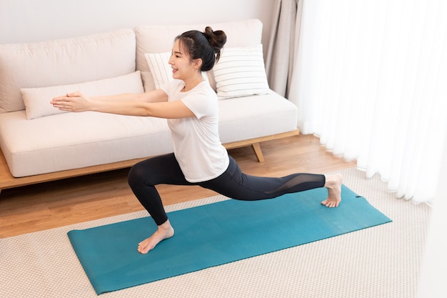 Productive activity concept a girl with a bun wearing the white t-shirt doing the difficult pilates move.