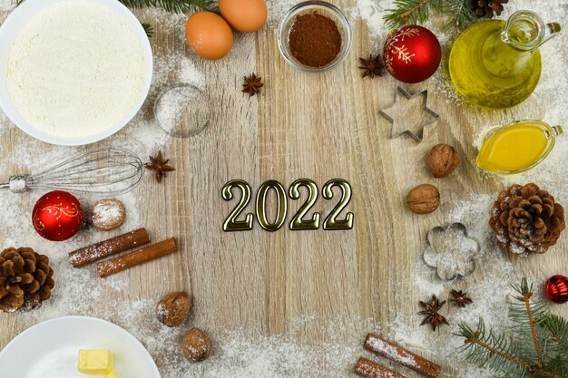 Products for baking homemade Christmas cookies on a wooden background with the inscription 2022.