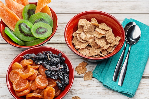 Products for healthy breakfast. Wooden bowls with nuts, dried fruits. Cereal flakes with milk.