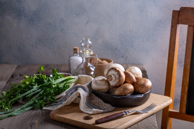 Products for the preparation of mushroom dishes. Champignons, dill, parsley, green onions on a wooden table. Cooking concept