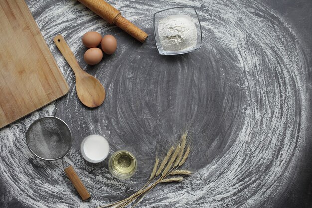 Products and tools for baking bread or cakes on a gray table in scattered flour