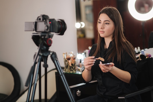 Profession make up artist woman reviewing beauty products on a videoo blog at beauty studio. Woman