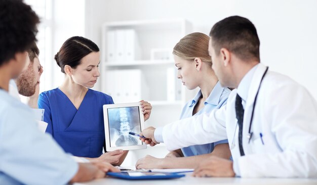 profession, people, surgery, radiology and medicine concept - group of doctors with x-ray on tablet pc computer screen meeting at medical office