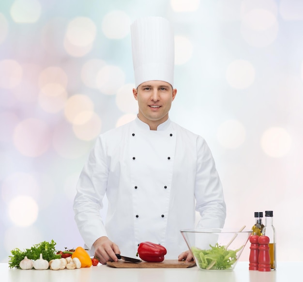 profession, vegetarian, food and people concept - happy male chef cooking vegetable salad over blue lights background