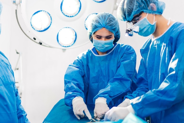 Professional anesthesiologist doctor medical team and assistant preparing patient to gynecological surgery performing operating with surgery equipment in modern hospital operation emergency room