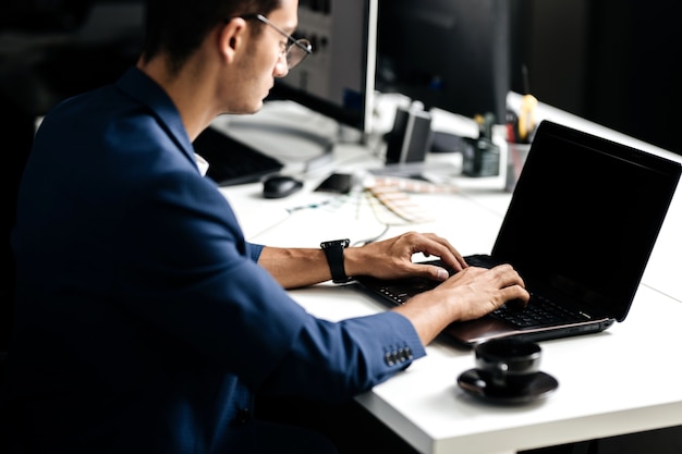 Professional architect dressed in a business suit talking by phone and works on the laptop in the office .