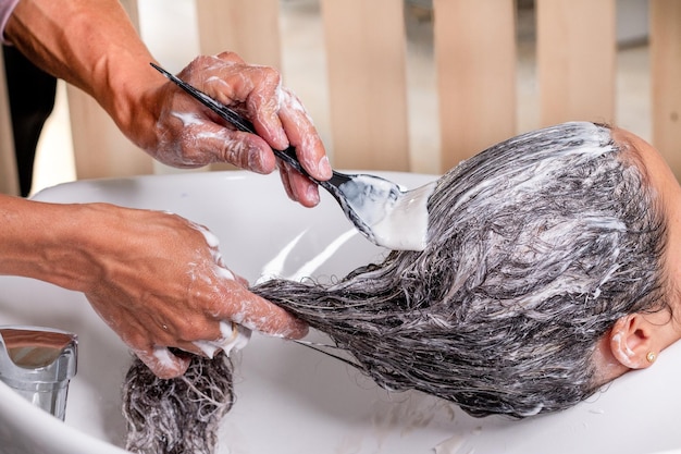 Professional artist applying dye with a brush on a woman's curly hair Professional beauty salon