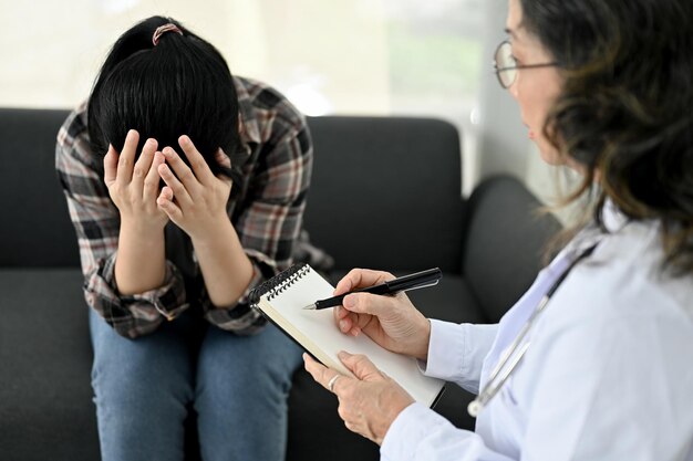 Professional Asian aged female psychiatrist or psychologist talking and diagnosis a female patient