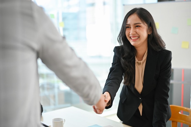 Professional Asian businesswoman shaking hands with a businessman