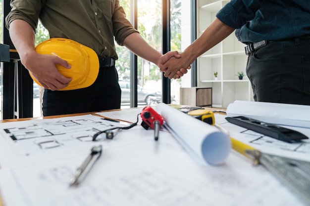 Professional Asian male engineer shaking hands with male architect after the meeting is over at office