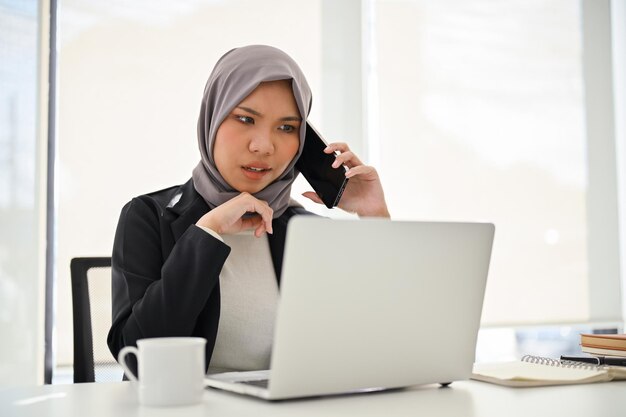 Professional Asian Muslim businesswoman unsatisfied complains to her employee over the phone