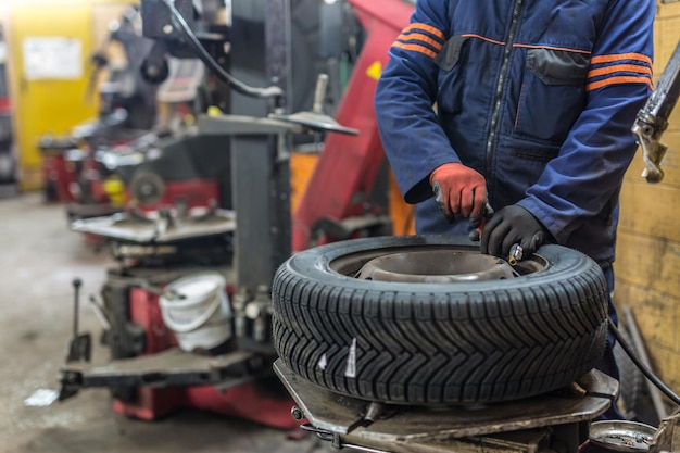 Professional auto mechanic replacing tire on wheel in car repair service