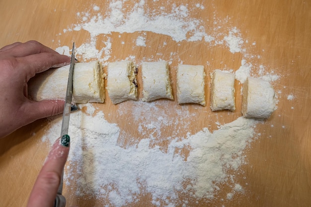 Professional baker with knife cuts the raw sausage dough into even small pieces