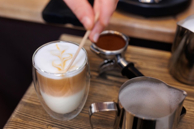 Professional barista pours fresh milk into a coffee cup creating a beautiful pattern