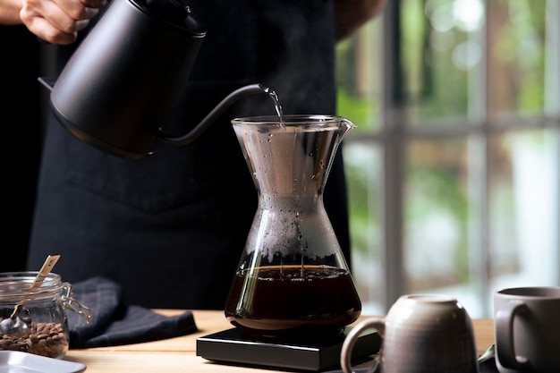 Professional barista preparing coffee using chemex pour over coffee maker and drip kettle Alternative ways of brewing coffee Coffee shop concept