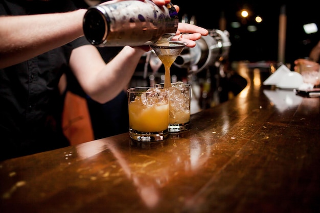 A professional bartender pours ice into a glass for drinking Time for a party in a nightclub