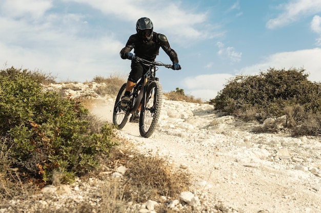 Professional bike rider fully equipped with protective gear during downhill ride on his bicycle