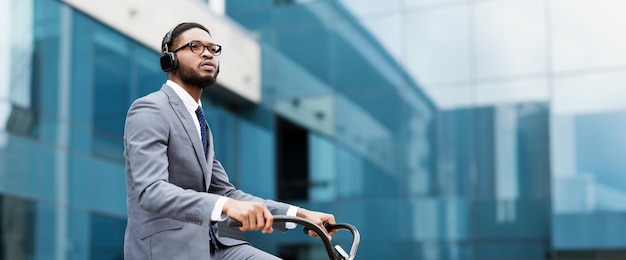 A professional black guy is on a bicycle in a bustling city the scene is lively and dynamic showing