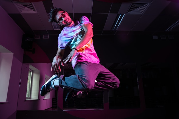 Professional break dancer in motion, practicing modern hip-hop dance in pink neon light