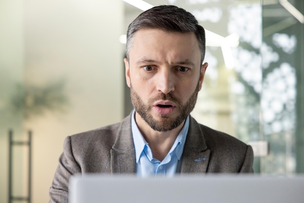 A professional businessman concentrates deeply while working on his laptop in a welllit contemporary