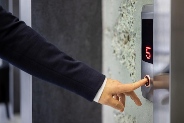 A professional businessman in a dark suit pressing an elevator button symbolizing convenience and