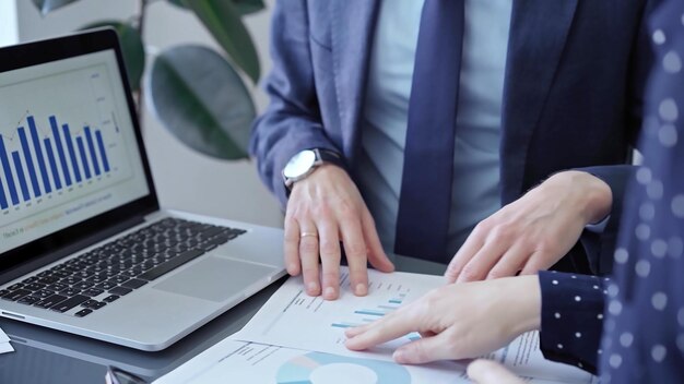 Photo professional businessman gestures to charts on laptop screen during corporate meeting business concept