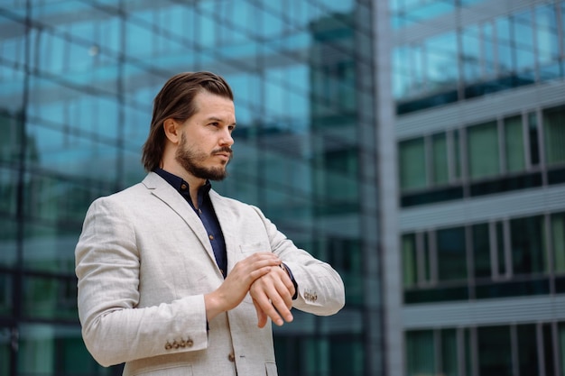 Professional businessman in suit looking at camera while standing on street with mobile phone App