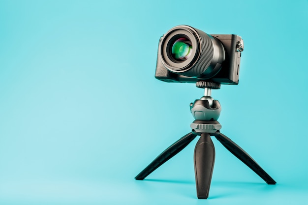 Professional camera on a tripod, on a blue background. Record videos and photos for your blog or report.