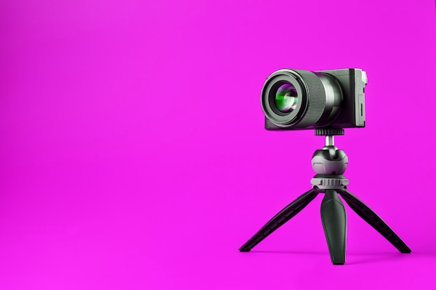 Professional camera on tripod, on pink. Record videos and photos for your blog or report.