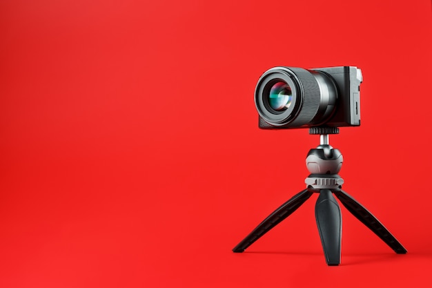 Professional camera on a tripod, on a red background. Record videos and photos for your blog, reportage