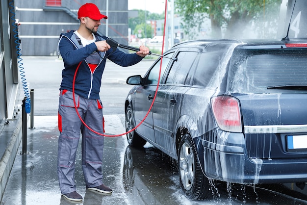 Professional car wash worker is washing client's car