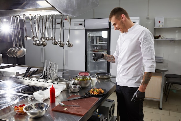 Professional chef cooking in the modern kitchen in hotel restaurant preparing shrimp salad