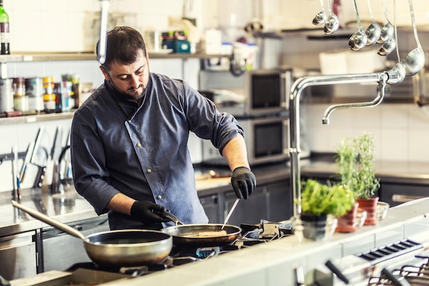 Professional chef cooks in the restaurant on two pans