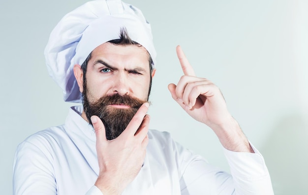 Professional chef pointing finger up pensive bearded man in cook uniform cooking food new idea