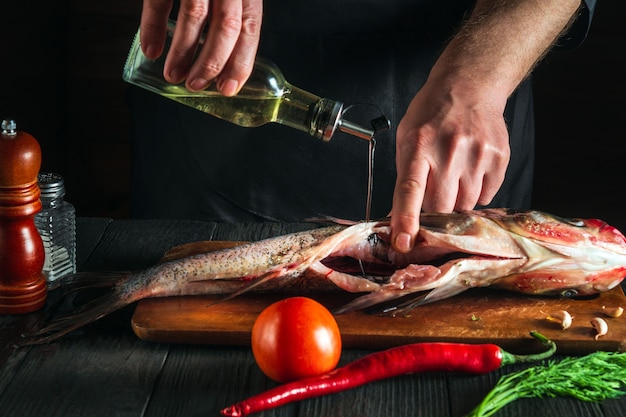 Professional chef prepares fresh fish bighead carp with add oil Preparing to cook fish food